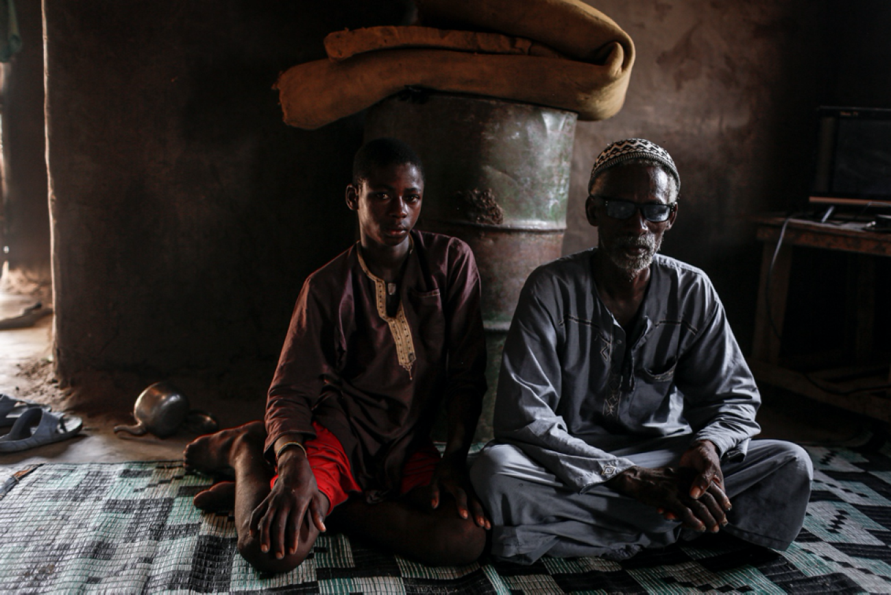 Adama Diamanka sits next to his father in their living room in the village of Sare Wali near Kolda