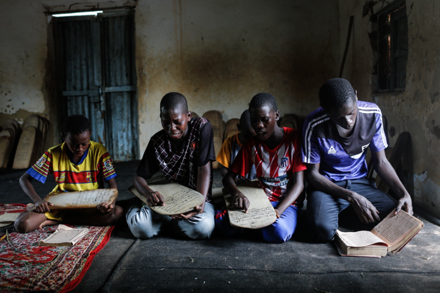 Talibé children recite passages from the Quran written on traditional wooden boards in a daara in Bignona