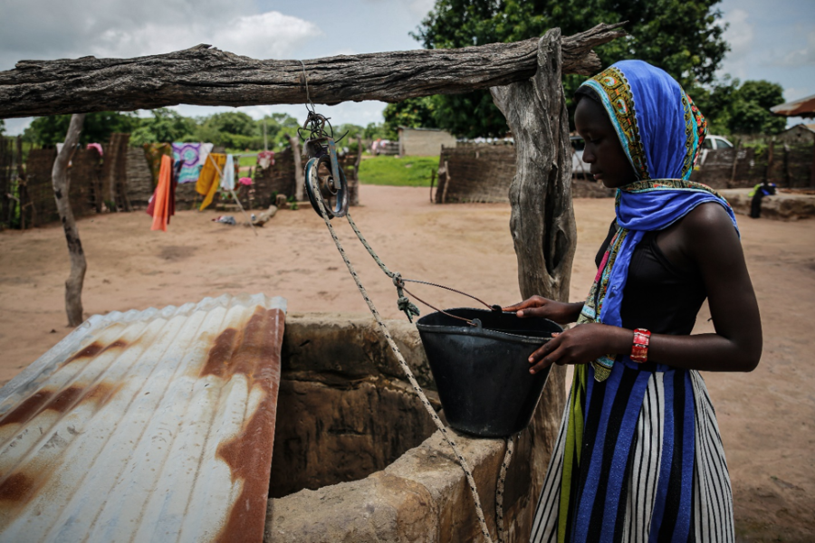 A girl pulls water from a well in a household of the Bloc Chantier village