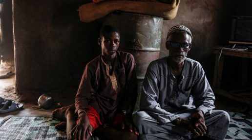 Adama Diamanka sits next to his father in their living room in the village of Sare Wali near Kolda